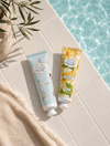 2 body butter tubes next to a pool