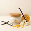 Butter baby container with vanilla beans, orange peels, and a wooden lid on a beige background